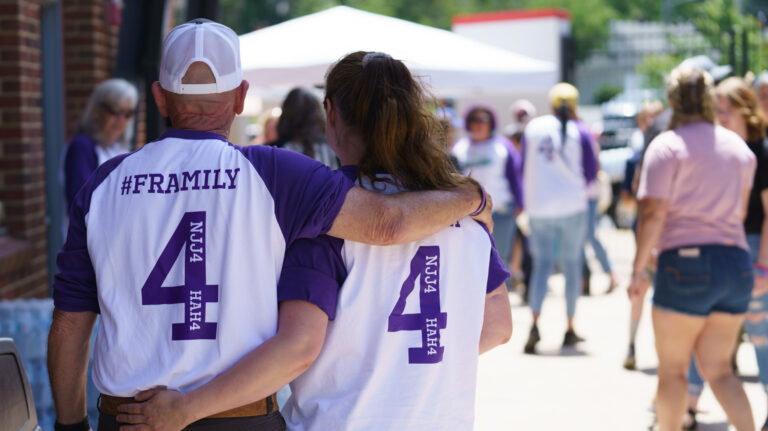 Two people hugging in baseball jerseys featuring the number 4 at our 2023 Safe At Home event